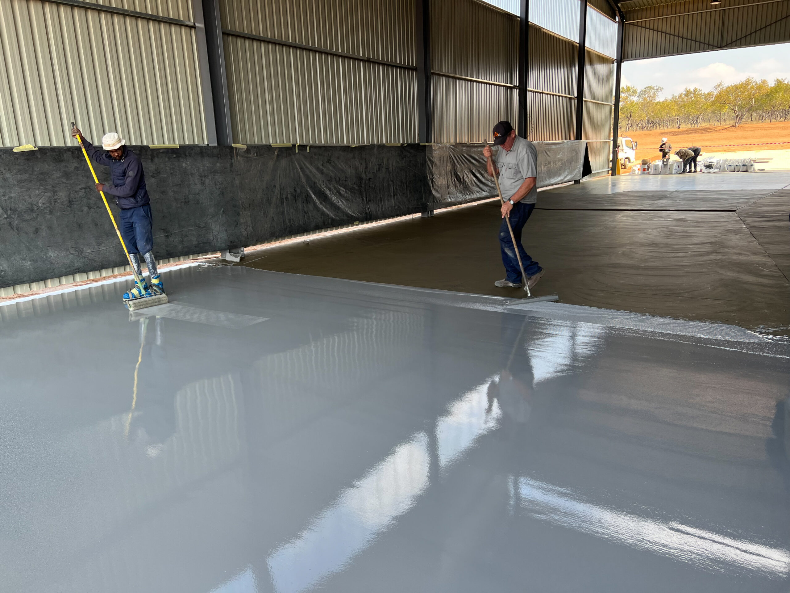 Workers providing epoxy flooring services South Africa in an industrial setting.